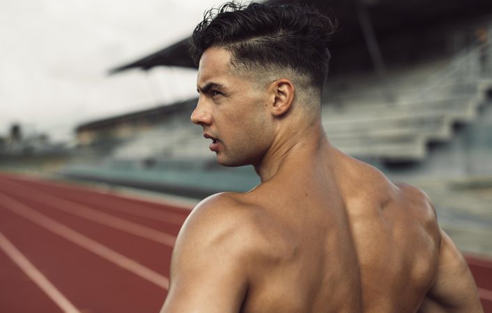 Rear view of healthy young man standing on track field