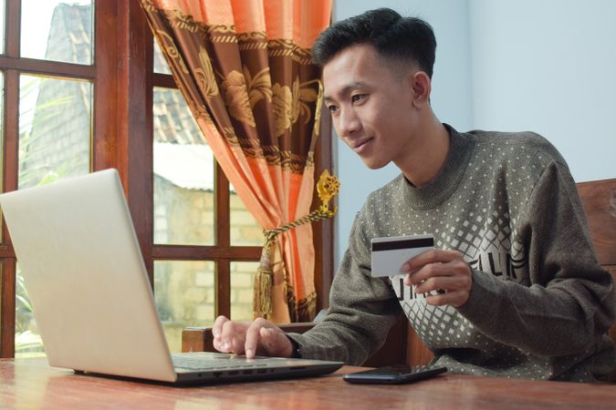 Asian man shopping online holding credit card and smartphone