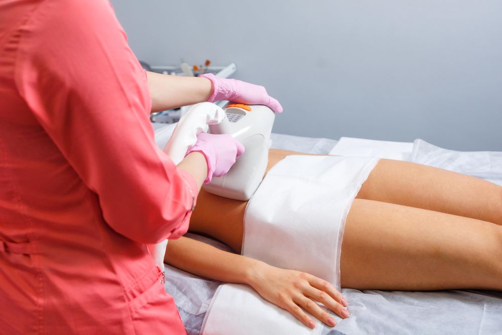 Cosmetologist doing beauty treatment on client’s stomach