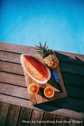 Fruit platter on a wooden board by the pool on a sunny day 65XOk0