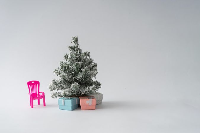 Snowy Christmas tree with presents underneath and pink chair