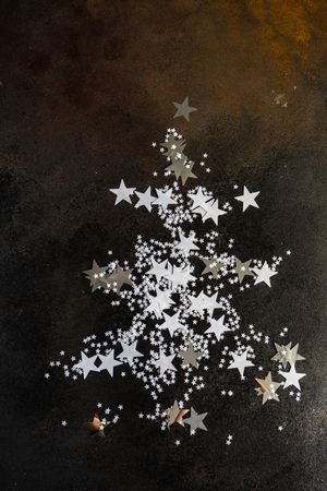 Christmas card concept of star confetti on table in shape of Christmas tree
