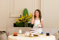 Birthday girl stands at decorated table with cake