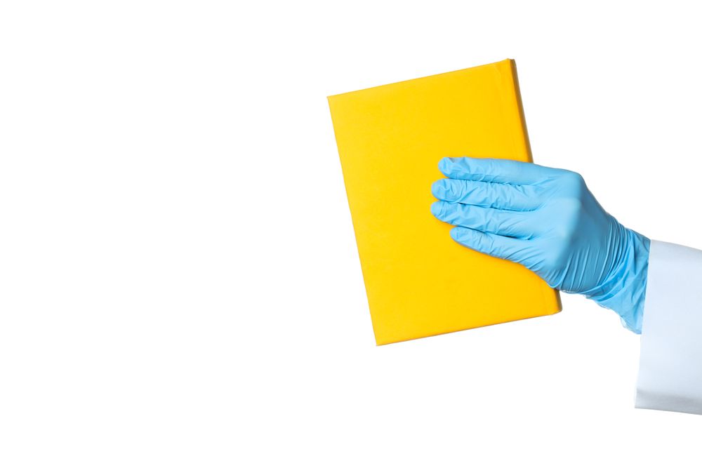 Doctors hand in glove holds book, isolated on white background