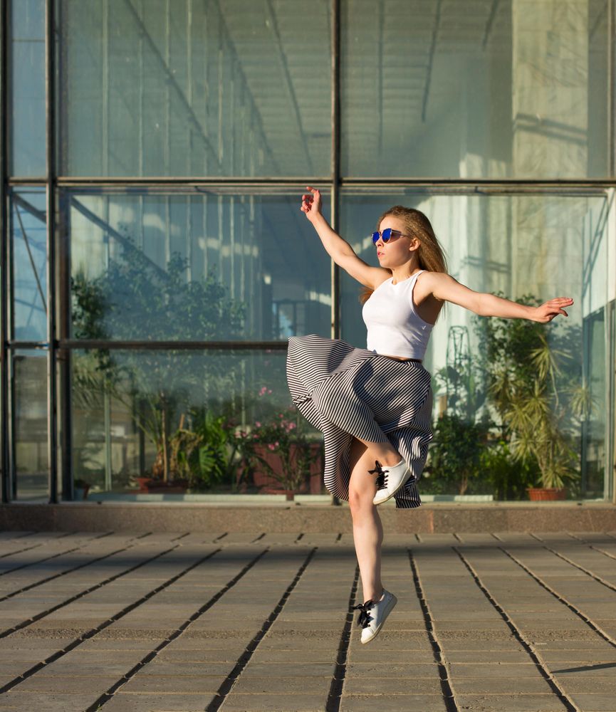 Female in skirt joyfully leaping in the sun