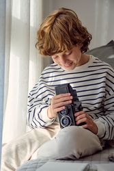 Smiling boy with aged photo camera on bed