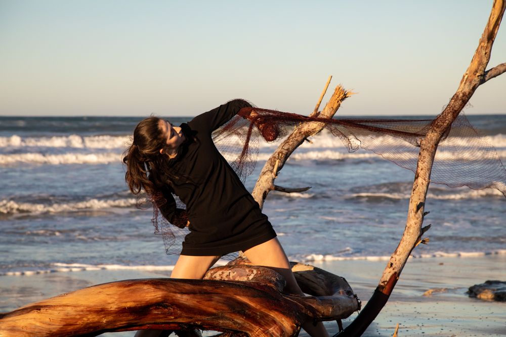 Woman in fishing net fixed on twig near water on shore