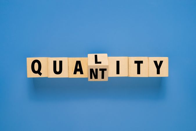 flip wooden blocks with quality and quantity words isolated on blue background