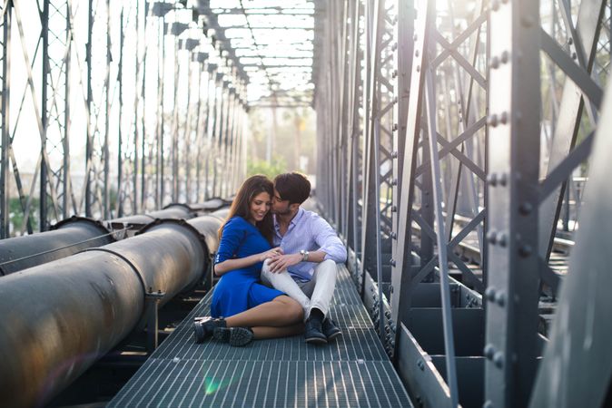 Amorous couple bonding on railway under bridge