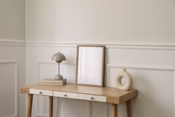 Trendy round vase, beige lamp and old books with mock up wooden picture frame
