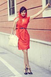 Elegant woman in dress with hand bag and heels holding onto into railing