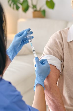 Crop doctor filling syringe with vaccine against patient in room