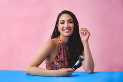 Elegant Hispanic woman with long brown hair holding large make up brush