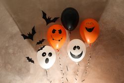 Different balloons on brown background. Halloween concept, space for text