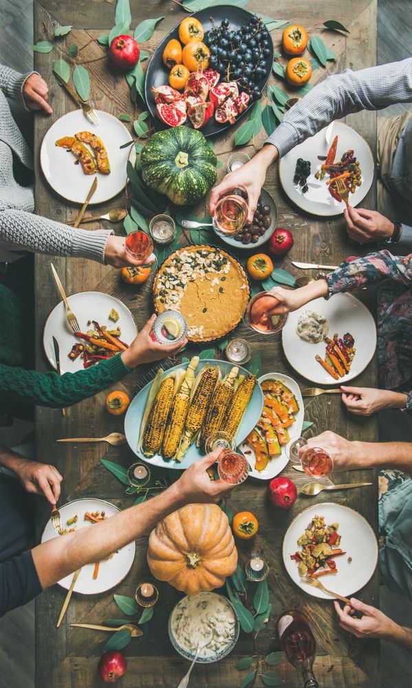 Group of people with wine glasses over festive vegetarian table with pie, vertical composition