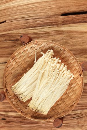Bamboo basket of fresh golden needle mushrooms, top view