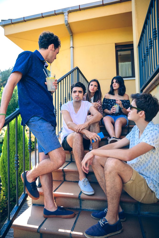 Young people talking outdoors sitting on stairs on sunny day