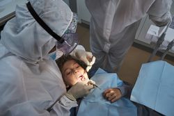 Dentists examining preteen patient in medical office