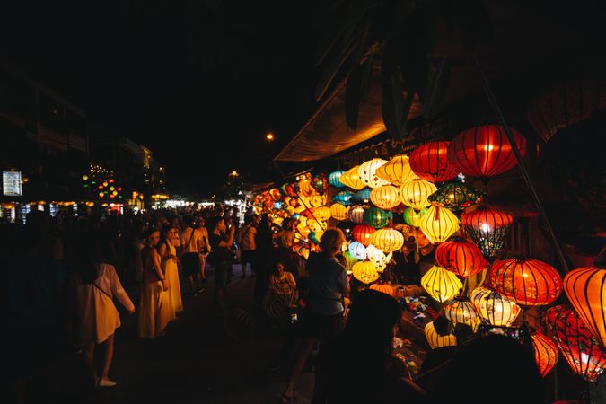 People walking in street market selling paper lanterns during night time