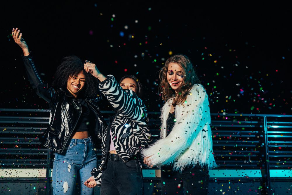 Multi-ethnic group of female friends at dancing at party with confetti