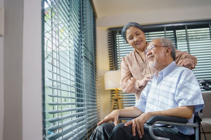 Asian woman gives massage to mature husband in wheelchair