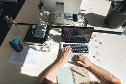 Crop man using laptop at workplace