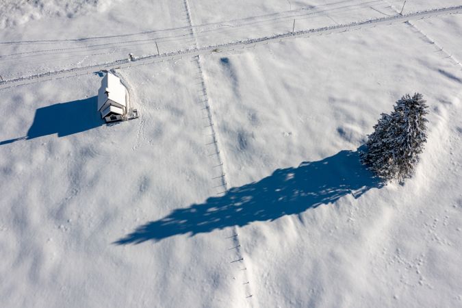 Snow-covered church in bright light, winter aerial view in the Bavarian Alps, Germany