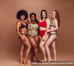 Full length of multiracial women in swimsuits looking at camera and smiling 4AW1Q0