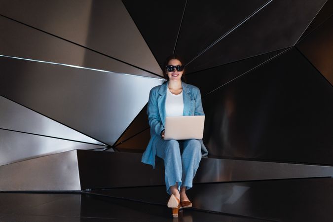 Woman in sunglasses browsing laptop in studio