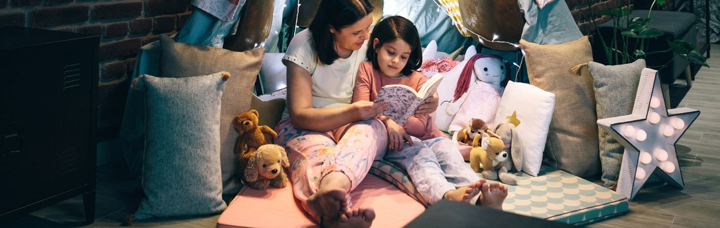 Mother and daughter having a pajama party reading a book