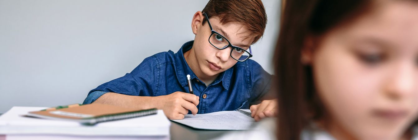 Teen writing in notebook at school