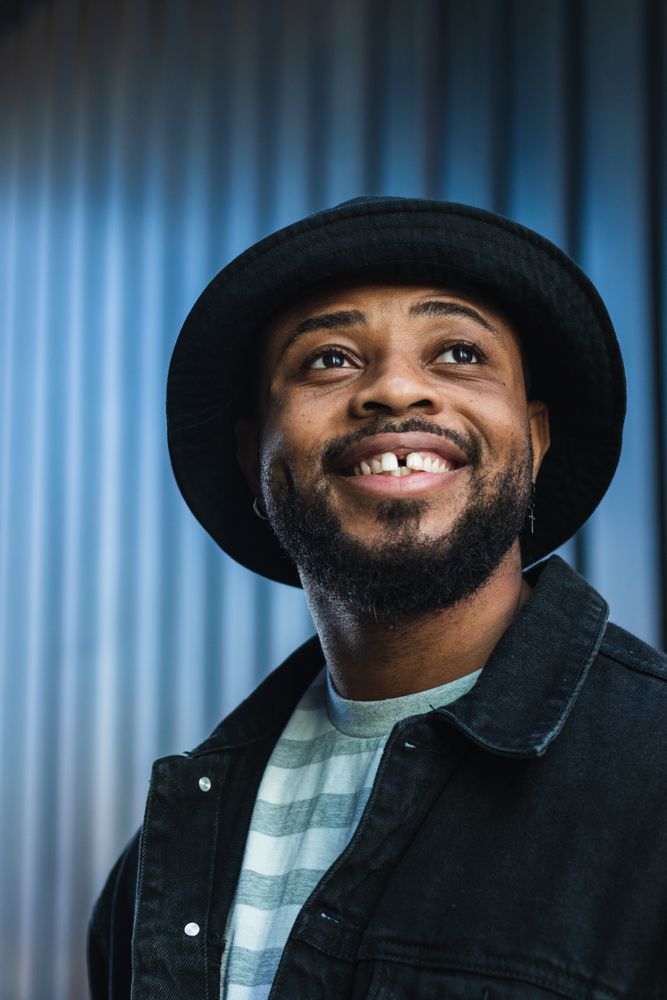 Smiling Black hipster man in hat looking up