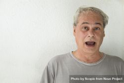 Portrait of surprised middle aged man in gray shirt against light background 5lK160