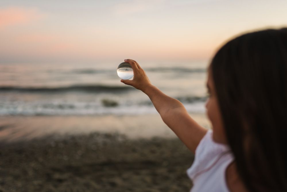 Girl playing with glass ball on seaside
