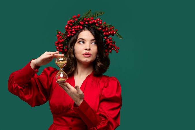 Woman in red dress with berry wreath holding hourglass