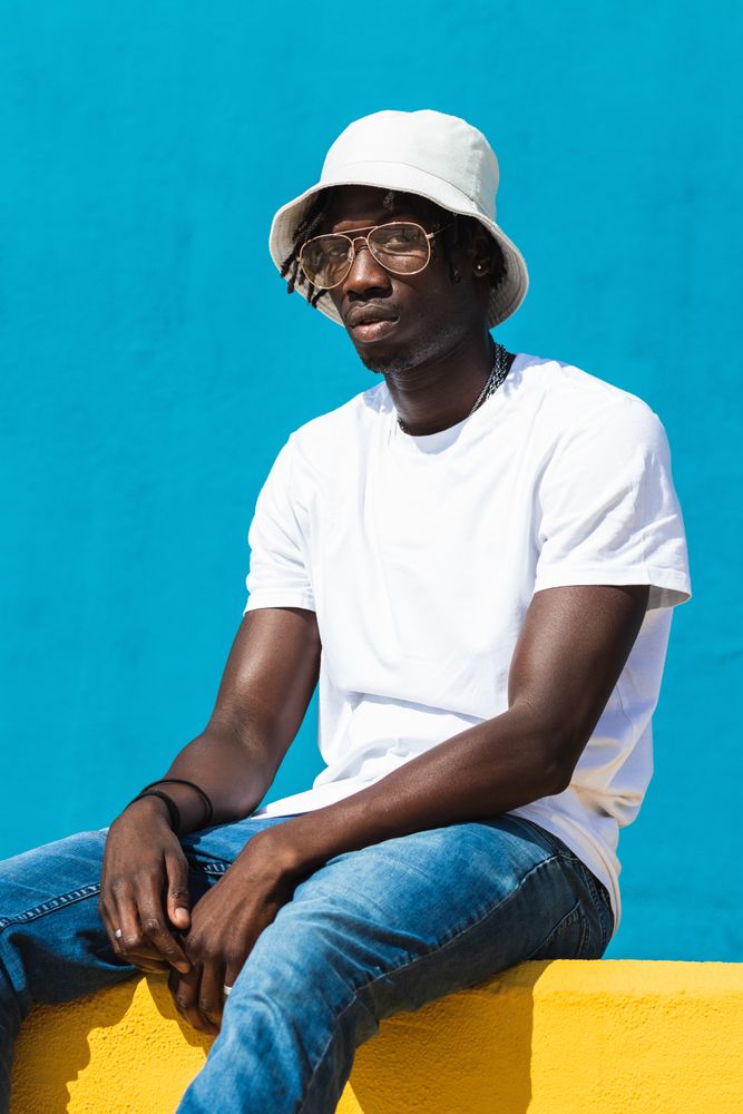 Black man sitting on colorful wall
