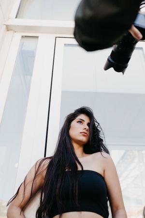 Crop photographer taking pictures of young model