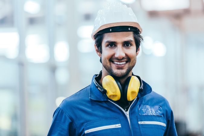 Happy male industrial engineer wearing safety helmet and uniform