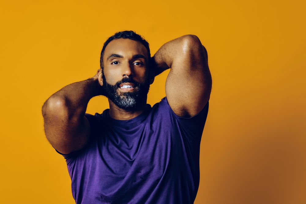 Black man in yellow studio with arms behind his head
