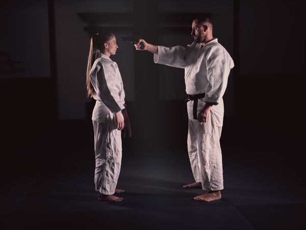 Man pointing gun to head of woman on training