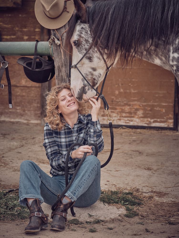 Cheerful woman caressing horse in paddock