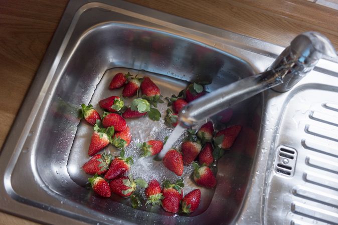Cleaning pile of strawberries in the kitchen sink