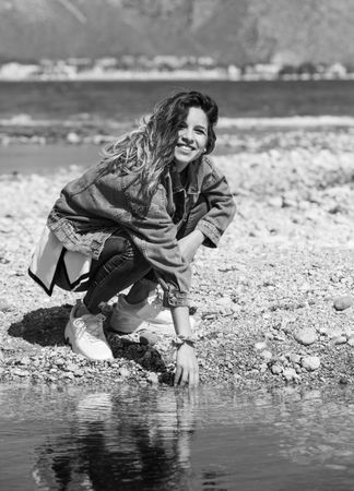 Young woman playing with water on shore
