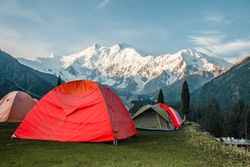 Red tents over looking snow capped mountains in Pakistan