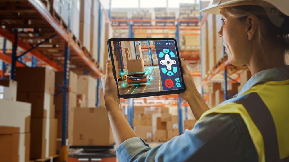 Future Technology Concept: Female Worker Holding Tablet With AR Remote Control Application For Retail Warehouse AGV Robot with Infographics.