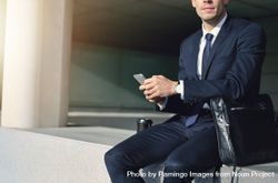 Man in business attire holding cell phone with leather computer bag 5anLd4