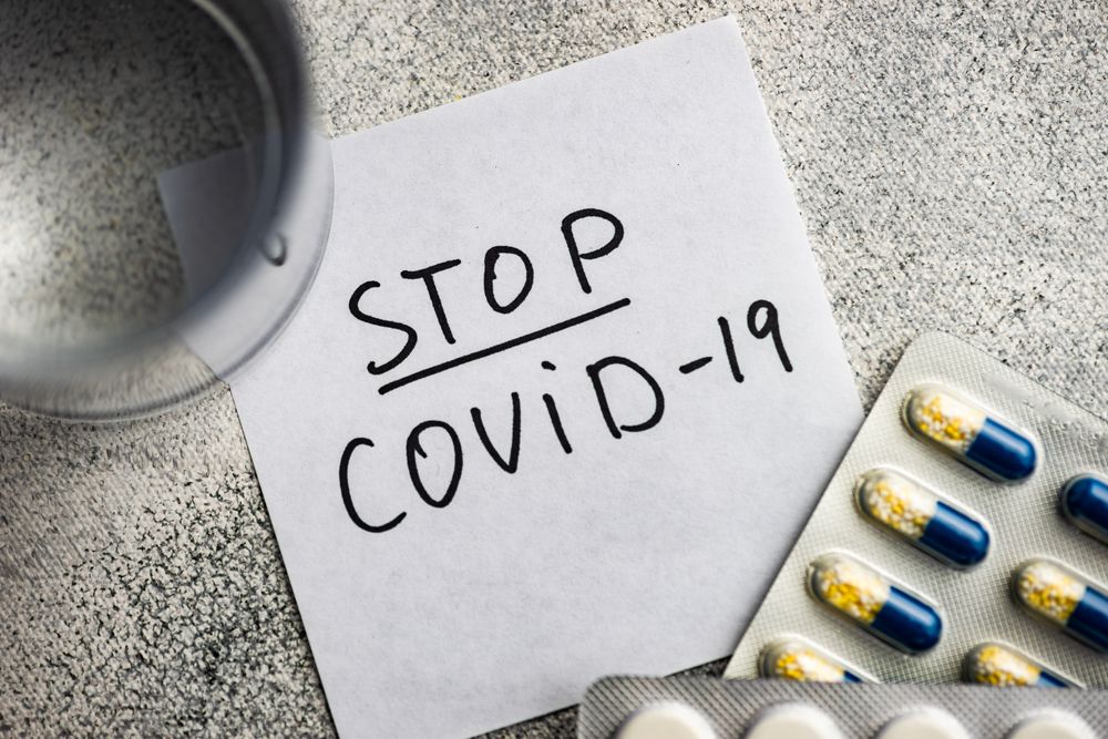 Top view of pills and glass of water with covid-19 note