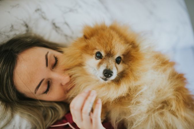 Smiling woman lying in bed with dog