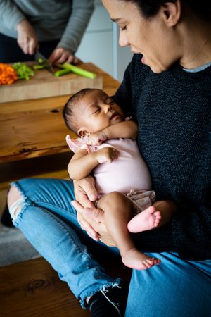 Baby in mother’s lap on bench in kitchen