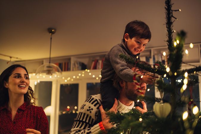 Family decorating Christmas tree together at home
